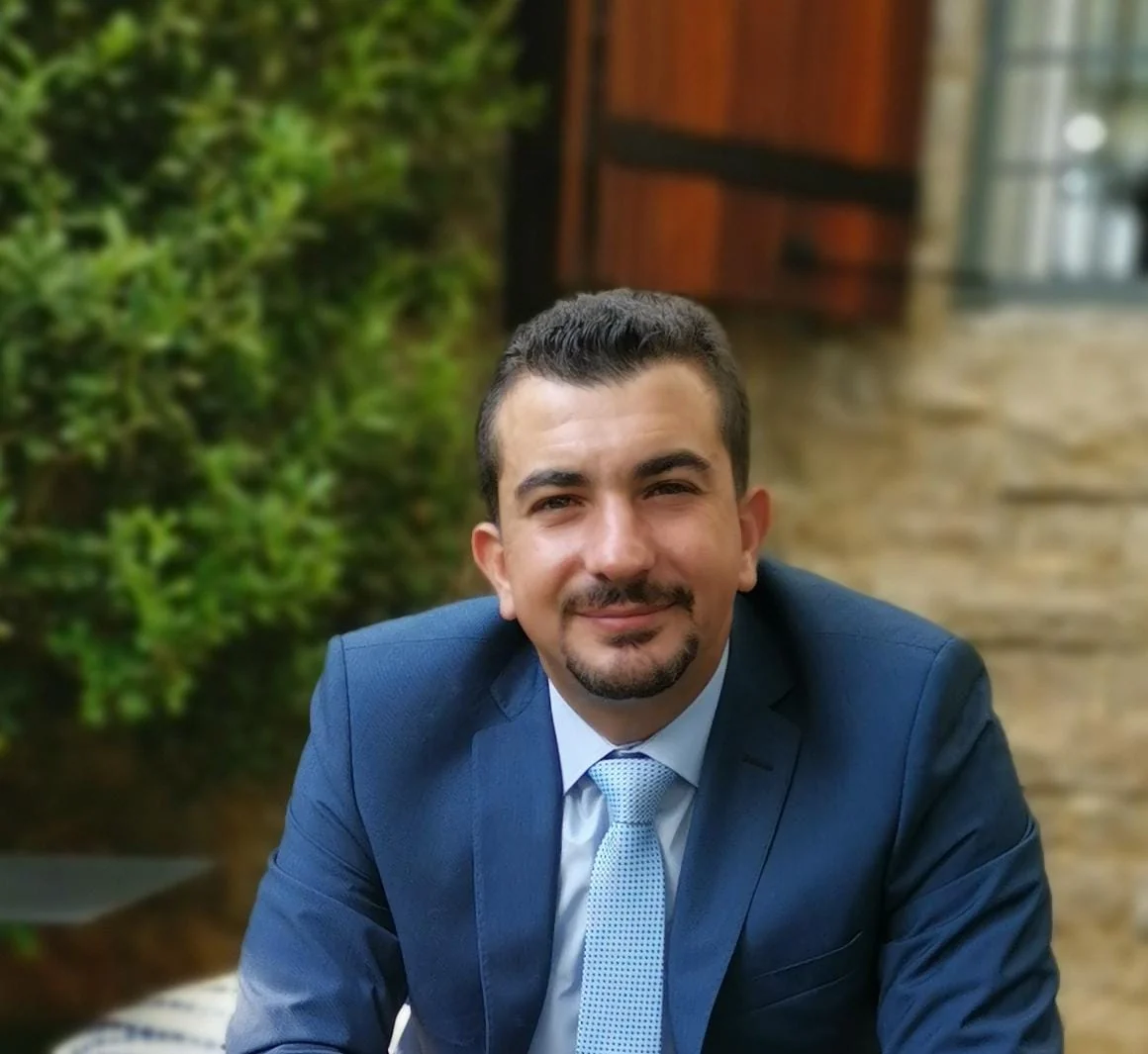 Portrait of Charbel Assaf in a navy suit in a Lebanese stone courtyard